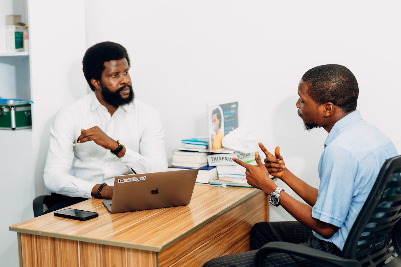 Home Two adults engaged in a professional consultation in a Lagos office, discussing business or healthcare topics.