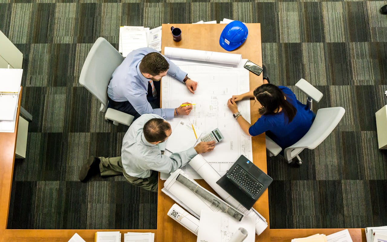 Services Top view of a team working on construction plans in an office setting.