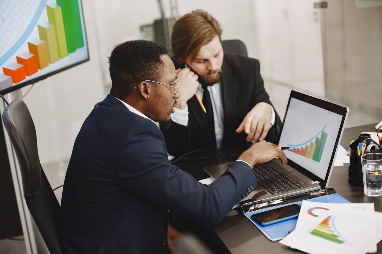 About Two business professionals working on growth charts using laptop in an office setting.